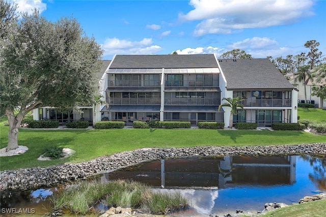 back of property featuring a water view and a lawn