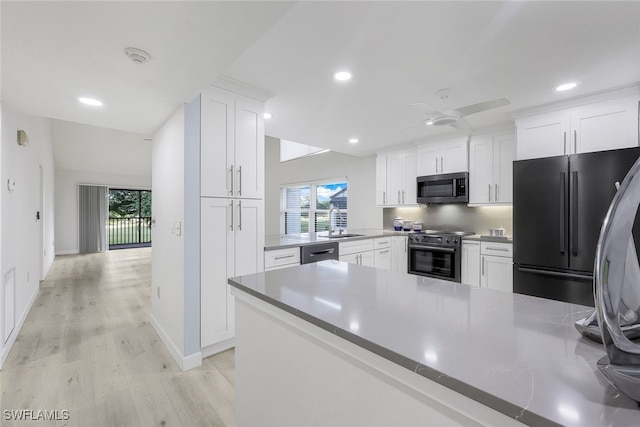 kitchen with white cabinets, light wood-style floors, stainless steel appliances, and a sink