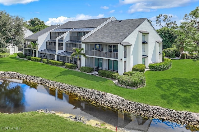 back of house with a water view, a standing seam roof, and a lawn