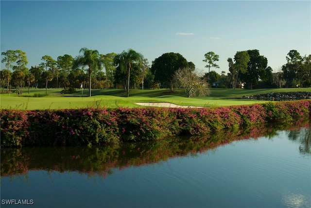 view of property's community featuring a water view, a lawn, and golf course view