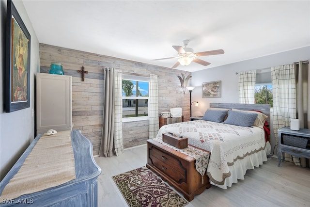 bedroom with light hardwood / wood-style flooring, ceiling fan, and wooden walls