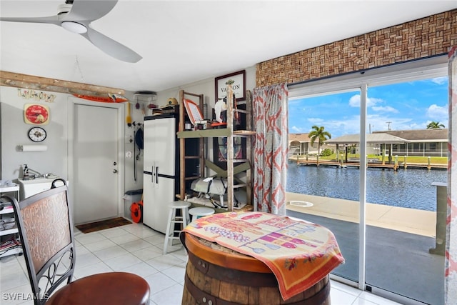 dining space with a water view, light tile patterned floors, and ceiling fan