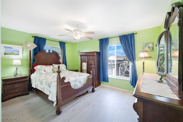 bedroom featuring light wood-type flooring, multiple windows, and ceiling fan