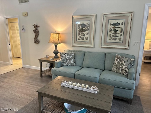 living area with visible vents, baseboards, and wood finished floors