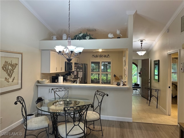 dining space featuring ornamental molding, wood-type flooring, and a notable chandelier