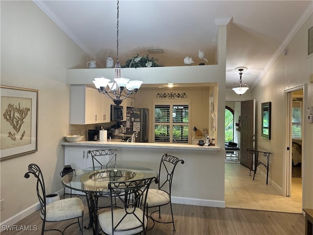 dining room featuring a chandelier, crown molding, light wood-style flooring, and baseboards