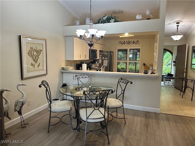 dining room featuring wood-type flooring, an inviting chandelier, and ornamental molding