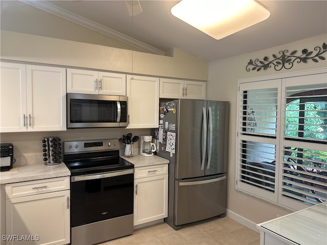 kitchen featuring light tile patterned floors, stainless steel appliances, ornamental molding, lofted ceiling, and white cabinets