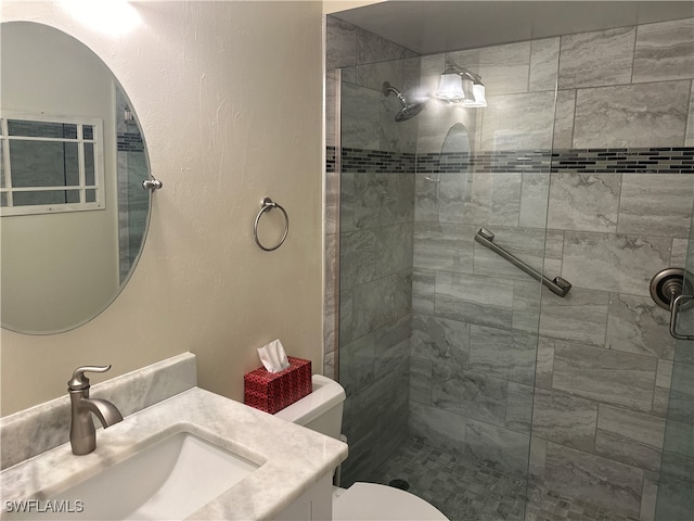 bathroom featuring a shower with door, vanity, and toilet