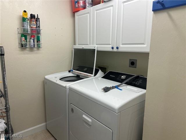 laundry room with independent washer and dryer, cabinets, and light tile patterned flooring