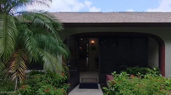 doorway to property with a shingled roof