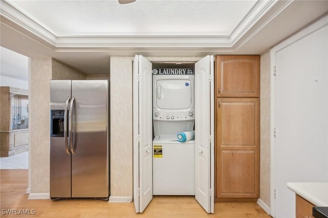 clothes washing area with crown molding, stacked washer / drying machine, and light hardwood / wood-style floors