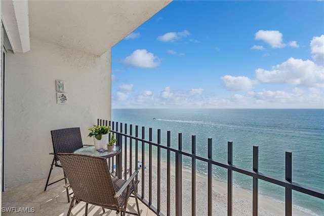 balcony featuring a view of the beach and a water view