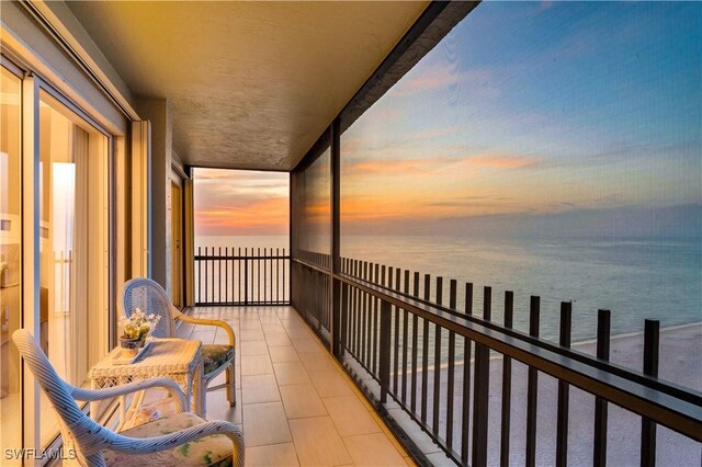 balcony at dusk featuring a water view