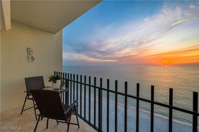 balcony at dusk with a beach view and a water view