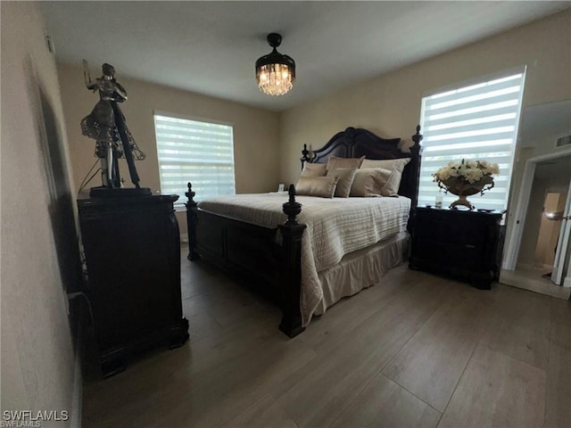 bedroom with hardwood / wood-style flooring, a notable chandelier, and multiple windows