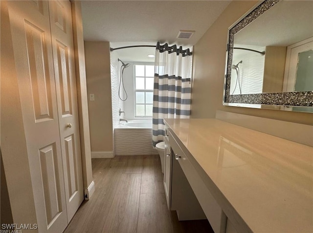 full bathroom with hardwood / wood-style floors, toilet, shower / bathtub combination with curtain, and vanity