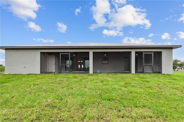 rear view of property featuring a sunroom and a lawn