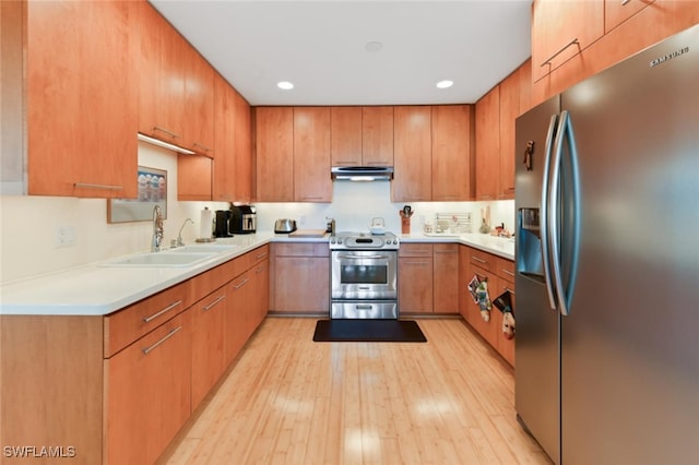 kitchen with appliances with stainless steel finishes, light hardwood / wood-style floors, and sink