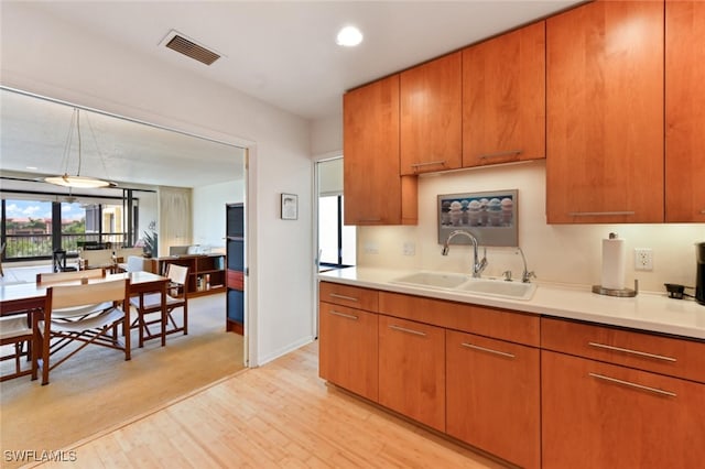 kitchen featuring sink, decorative light fixtures, and light hardwood / wood-style floors