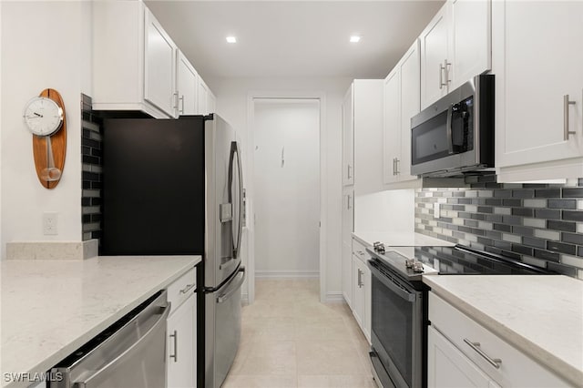 kitchen featuring stainless steel appliances, light tile patterned flooring, light stone countertops, and white cabinets