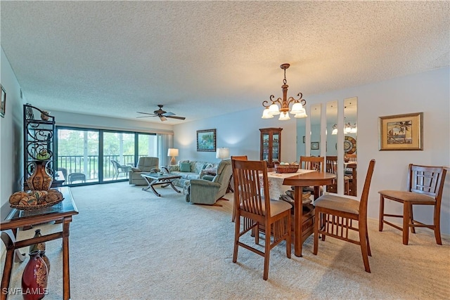 dining room featuring light carpet, baseboards, ceiling fan with notable chandelier, and a textured ceiling