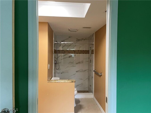 bathroom featuring tile patterned floors, toilet, and a tile shower