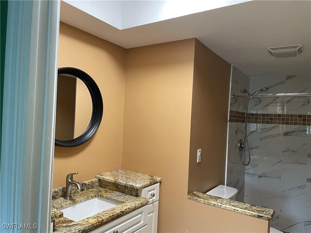 bathroom featuring vanity, toilet, and a tile shower