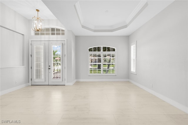 entrance foyer featuring a tray ceiling, crown molding, an inviting chandelier, and a wealth of natural light