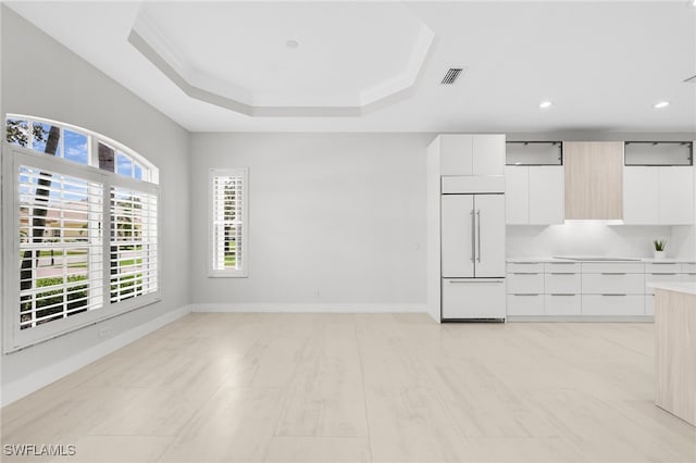 kitchen with a tray ceiling, white cabinetry, crown molding, and paneled built in fridge