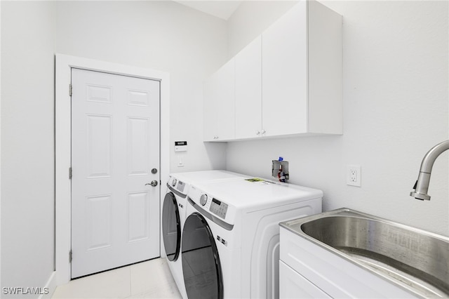 laundry area with washing machine and dryer, sink, cabinets, and light tile patterned floors