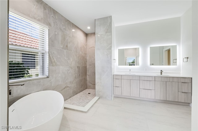 bathroom with tile walls, plenty of natural light, vanity, and independent shower and bath