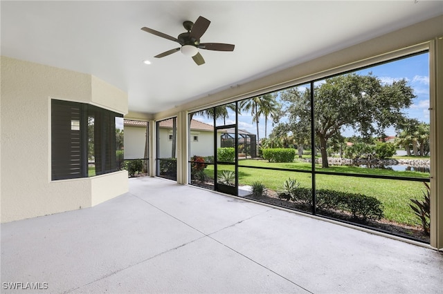 unfurnished sunroom featuring ceiling fan and a water view