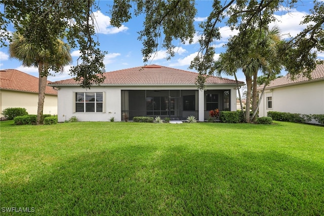 rear view of house featuring a sunroom and a lawn