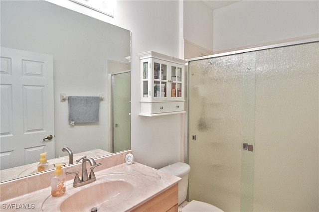 bathroom featuring a shower with shower door, toilet, and vanity