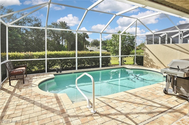 view of pool with a lanai, area for grilling, and a patio