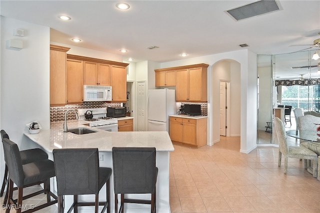 kitchen featuring white appliances, sink, kitchen peninsula, and ceiling fan