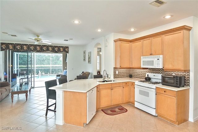 kitchen featuring a kitchen breakfast bar, white appliances, kitchen peninsula, sink, and ceiling fan