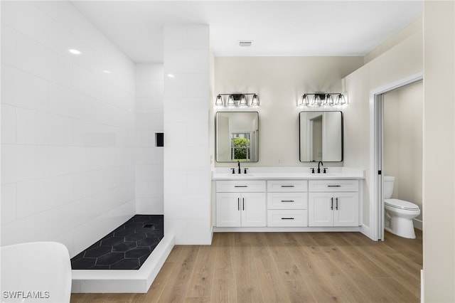 bathroom featuring vanity, wood-type flooring, toilet, and tiled shower