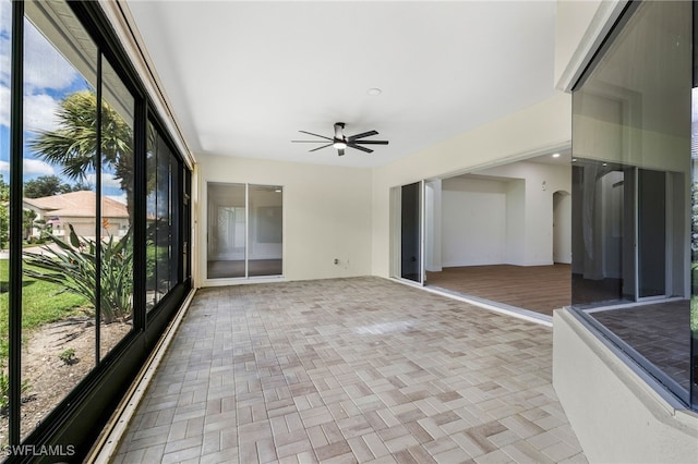 unfurnished sunroom featuring ceiling fan