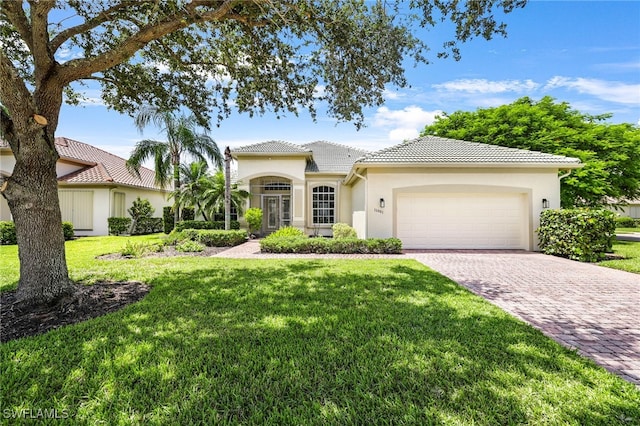 mediterranean / spanish-style home with a garage and a front lawn