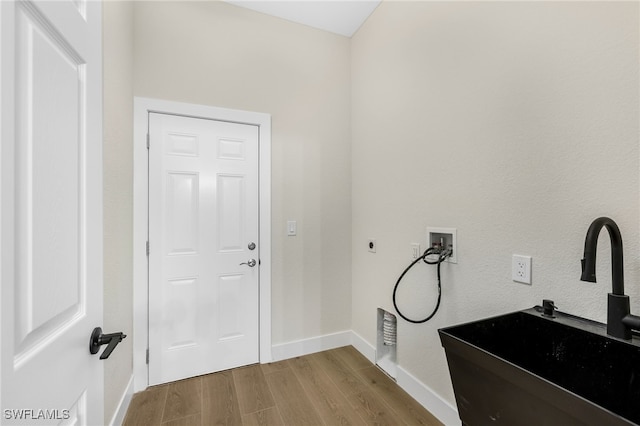 clothes washing area with washer hookup, sink, light hardwood / wood-style floors, and hookup for an electric dryer