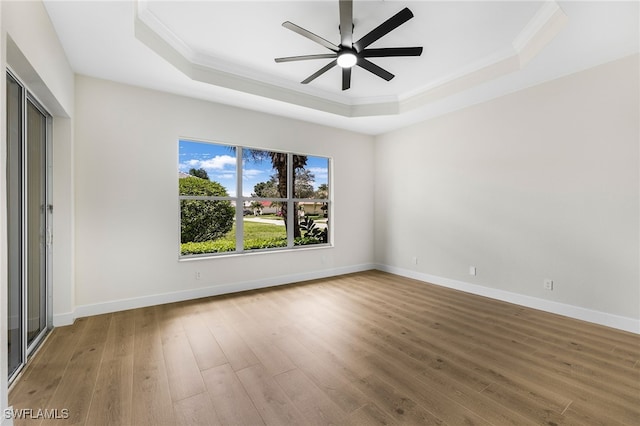 spare room featuring a raised ceiling, hardwood / wood-style floors, and ceiling fan