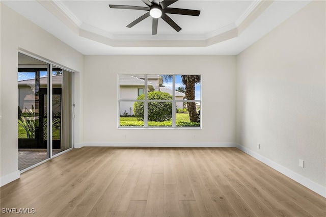 empty room featuring ceiling fan, crown molding, light hardwood / wood-style floors, and a tray ceiling