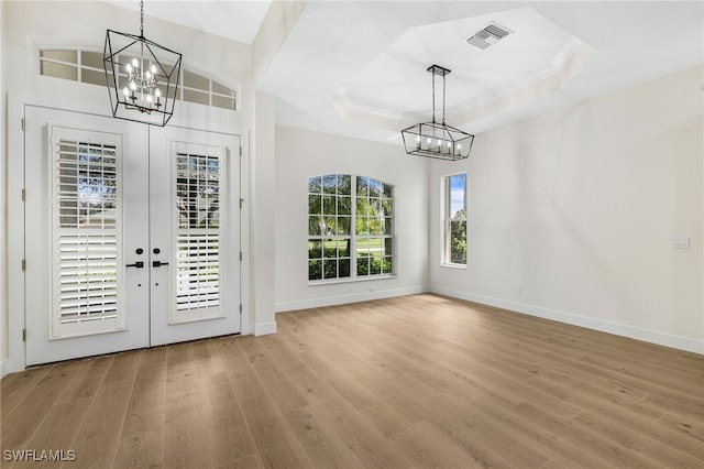 entrance foyer with an inviting chandelier, light hardwood / wood-style flooring, and a raised ceiling