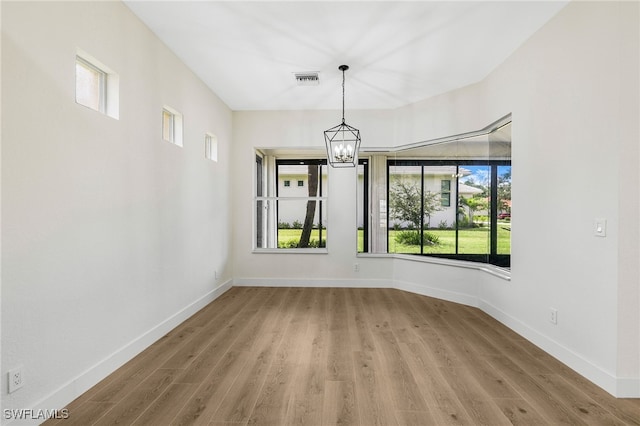 unfurnished dining area featuring hardwood / wood-style floors and an inviting chandelier