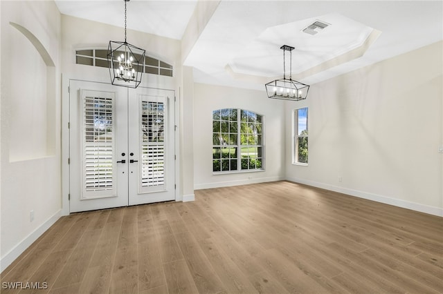 foyer featuring hardwood / wood-style floors, a tray ceiling, and a chandelier