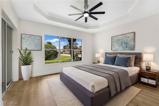 bedroom featuring ornamental molding, light hardwood / wood-style floors, a raised ceiling, and ceiling fan