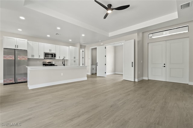 kitchen with white cabinets, stainless steel appliances, ceiling fan, and light hardwood / wood-style floors