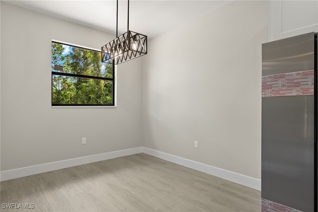 unfurnished room with light hardwood / wood-style flooring and an inviting chandelier